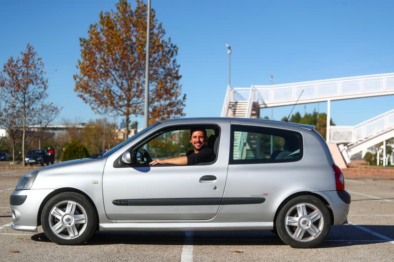 Cristian Lopez poses with his newly-bought 15-year-old second hand car in an empty parking lot in Madrid