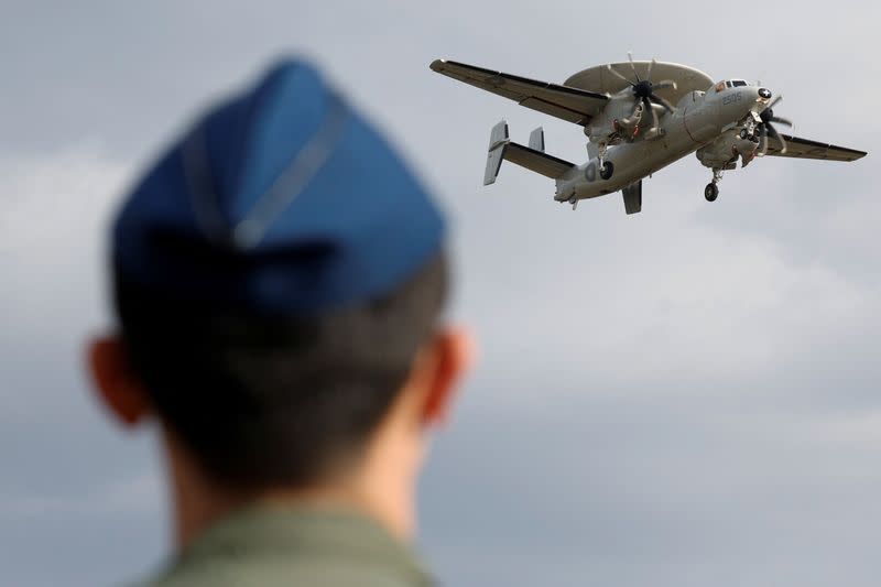 A member of the Taiwan Air Force looks on as an E-2K aircraft flies past during a demonstration for the media at the Pingtung air base in Pingtung