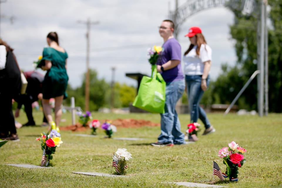 People place flower arrangements on graves Thursday at Veterans Cemetery in Oklahoma City.