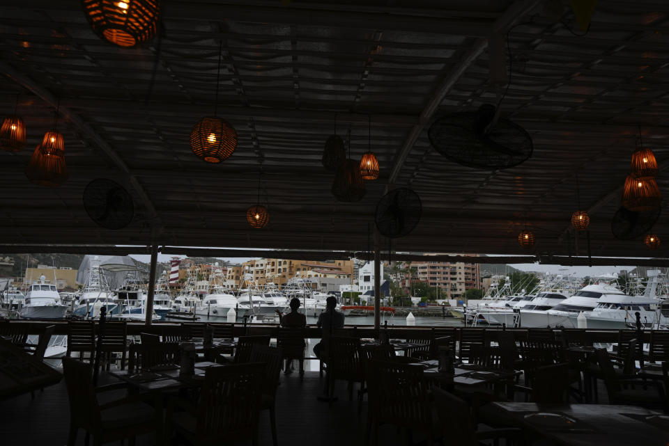 A couple tourists take a drink in a bar still open at the harbor of Cabo San Lucas, Mexico, Friday, Oct. 20, 2023. Hurricane Norma is heading for the resorts of Los Cabos at the southern tip of Mexico's Baja California Peninsula, while Tammy grew into a hurricane in the Atlantic. (AP Photo/Fernando Llano)