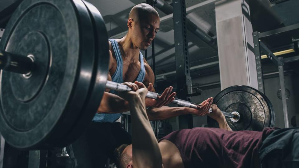 two friends exercising bench press in gym