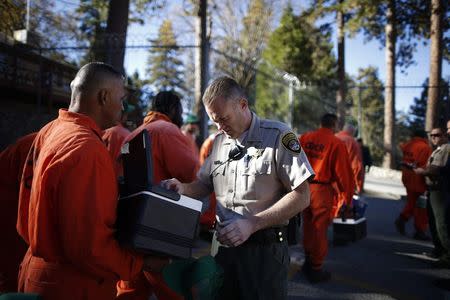 Correctional officer Tim Bruzzesi checks prison inmates' lunch boxes as they walk out of Oak Glen Conservation Fire Camp #35 to go to work projects in Yucaipa, California November 6, 2014. REUTERS/Lucy Nicholson