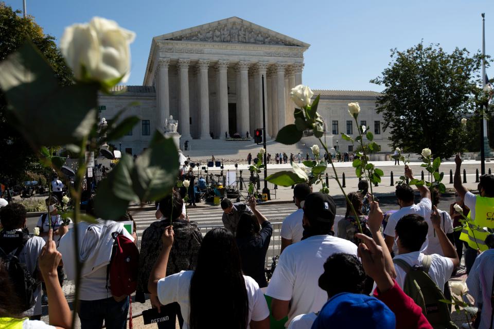 Mourners hold up white roses for Justice Ruth Bader Ginsburg at the steps of the U.S. Supreme Court Sept. 23.