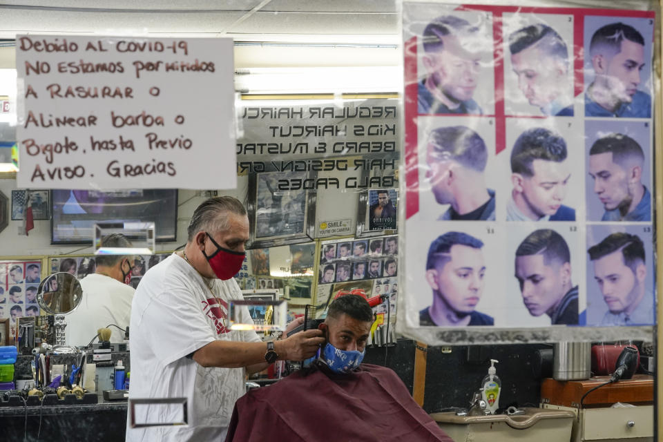 Edgar Gomez has his hair cut by George Garcia, owner of George's Barber Shop, Tuesday, July 14, 2020, in San Pedro, Calif. Gov. Gavin Newsom this week ordered that indoor businesses like salons, barber shops, restaurants, movie theaters, museums and others close due to the spread of COVID-19. (AP Photo/Ashley Landis)
