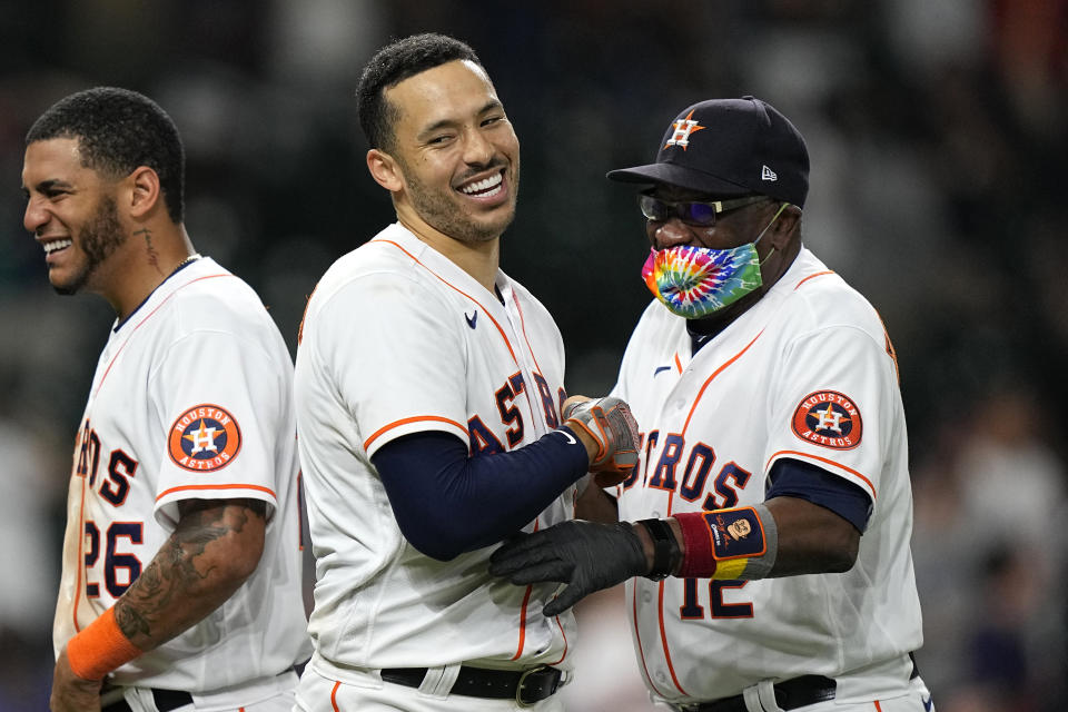 Houston Astros' Carlos Correa, center, celebrates with manager Dusty Baker Jr. (12) after hitting a game-winning RBI ground-rule double against the Seattle Mariners during the 10th inning of a baseball game Tuesday, Sept. 7, 2021, in Houston. The Astros won 5-4 in 10 innings. (AP Photo/David J. Phillip)