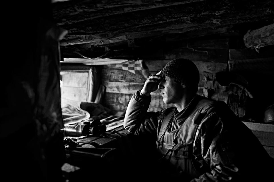 <p>An exhausted Ukrainian soldier reacts while observing enemy positions from a makeshift bunker at a position in a frontline around the village of Novotroitska, at the Mariupol sector in Donbas Oblast in Ukraine, in April 2017. (Photo: Manu Brabo/MeMo) </p>