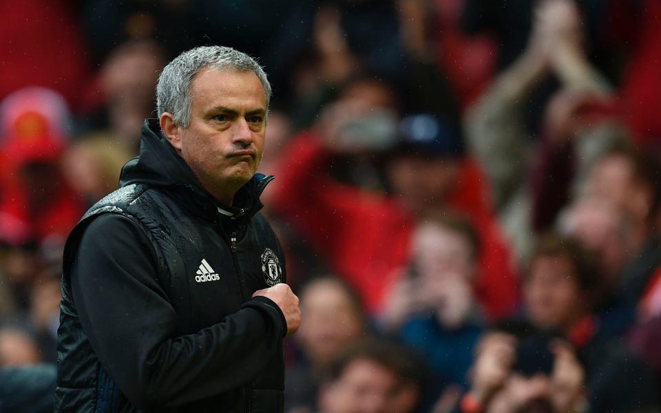 Manchester United's Portuguese manager Jose Mourinho points at the badge on his chest as he leaves the pitch - Credit: AFP