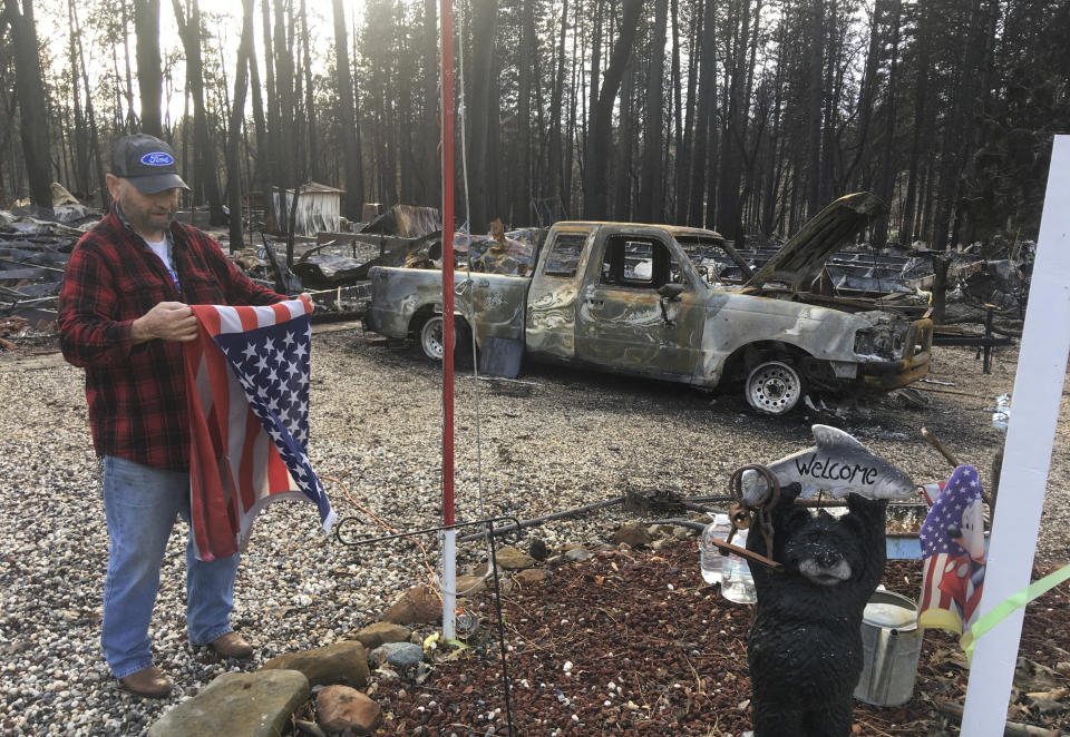 Jerry McLean folds the flag that was flying outside the remains of his home Wednesday, Dec. 5, 2018, in Paradise, Calif. Some residents of a California town devastated by a catastrophic wildfire nearly a month ago were finally allowed to return home to sift through the charred remains in search of precious family heirlooms, photos and other possessions. (AP Photo/Don Thompson)