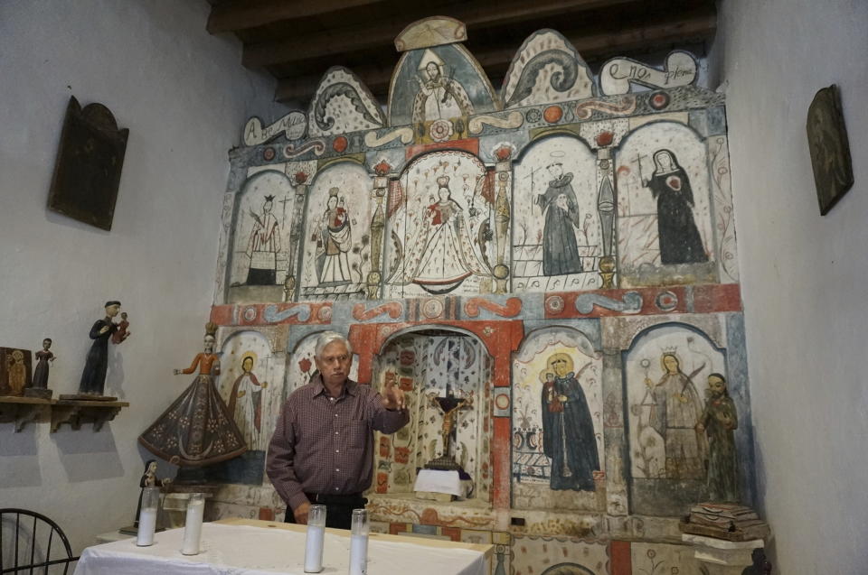 Master santero Felix Lopez – an artist trained in New Mexico's centuries-old tradition of religious sculpture and painting – speaks during an interview while standing in front of the 1810s 'reredo' or altarpiece he cleaned and preserved in the Holy Rosary Mission Church in Truchas, New Mexico, Sunday, April 16, 2023. "You never heard English here," said Lopez of growing up in the 1950s in Truchas, a ridgetop village between Santa Fe and Taos. (AP Photo/Giovanna Dell'Orto)