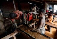 FILE PHOTO: An informal gold miner pours water over ground-up rock at an angle to wash the heavier gold elements to the bottom at the site of Nsuaem-Top