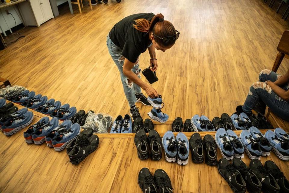 A migrant mother of three looks at running shoes in June 2023 that were donated to the group in Sacramento after they were transported to the city from El Paso, Texas, on two plane flights by a Florida contractor.