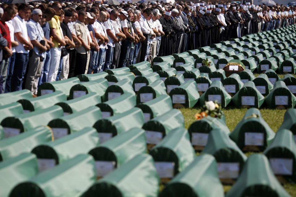 Bosnian Muslims pray near the coffins of relatives during a mass funeral for bodies found in a mass grave, in Kozarac, near Prijedor, July 20, 2014. (REUTERS/Dado Ruvic)