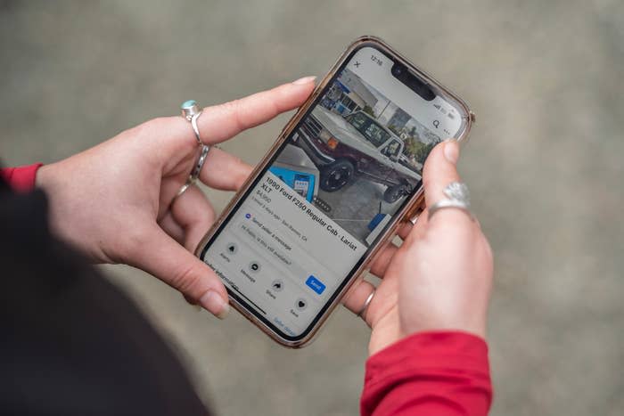 Hands holding a phone displaying a social media post about a car parked on a sidewalk