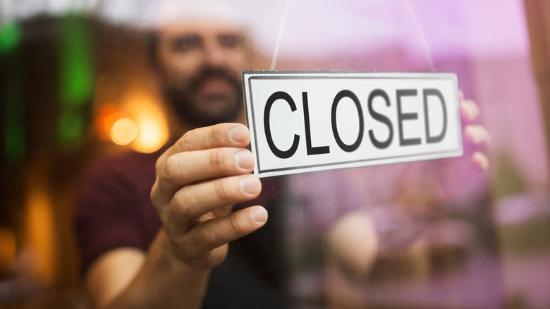 Man putting up closed sign 