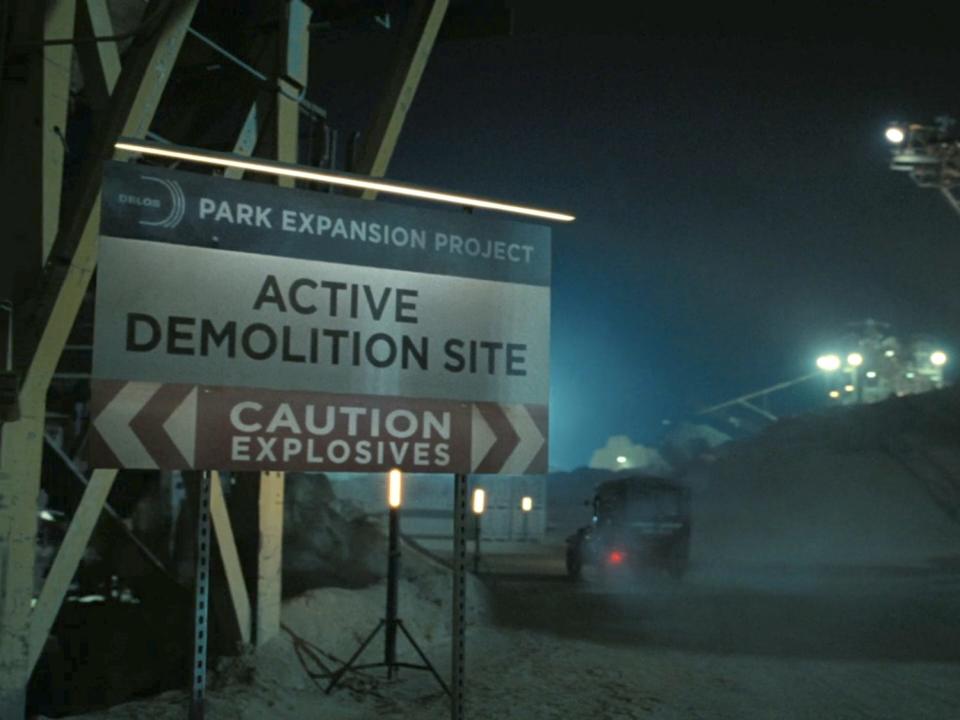 A sign saying "ACTING DEMOLITION SITE" with a car driving past.