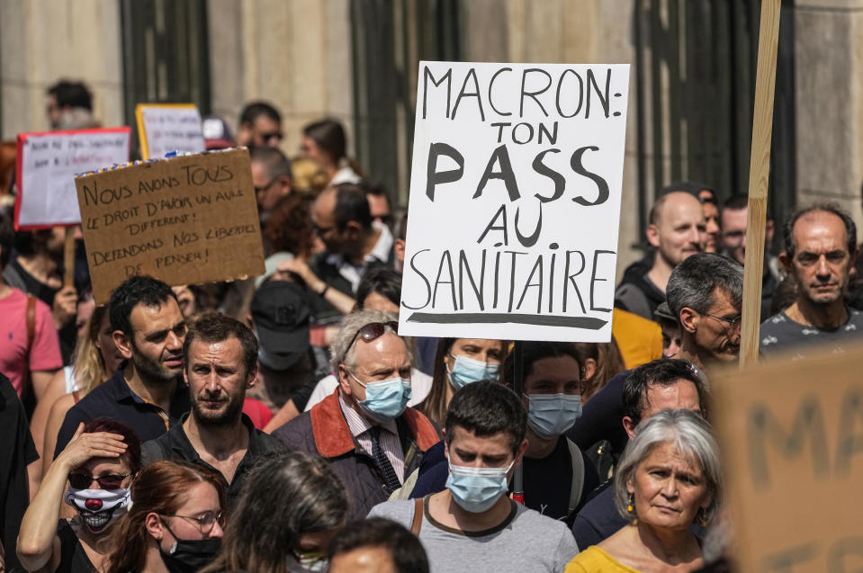 Anti-vaccine protester holds a placard that reads Macron your health pass into the toilet march during a rally in Paris, Saturday, July 17, 2021. Tens of thousands of people protested across France on Saturday against the government's latest measures to curb rising COVID-19 infections and drive up vaccinations in the country. (AP Photo/Michel Euler)