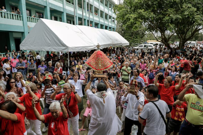 A priest carries a statue of Baby Jesus during a Catholic mass for residents affected by the erupting Taal Volcano in an evacuation center, in Tagaytay City