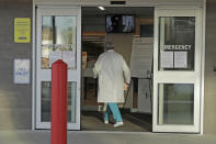 Dr. Stephen Anderson, a physician who works in the Emergency Department at the MultiCare Auburn Medical Center in Auburn, Wash., carries his mask as he walks into the emergency entrance to begin his shift, Tuesday, March 17, 2020, in Auburn, Wash., south of Seattle. Anderson said he writes messages on his shields to identify them as his, and this morning he chose the phrase "Stay Safe." “There just are not enough masks to go around at my hospital,” said Dr. Anderson. "I've got a two-day supply of masks so we're trying to be conservative. You get one in the morning. You clean it and reuse it." (AP Photo/Ted S. Warren)