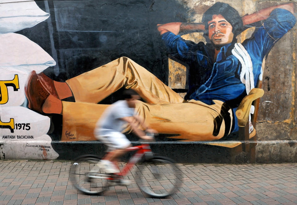 An Indian cyclist rides past a mural of Bollywood actor Amitabh Bachchan from his classic film 'Deewar' on the eve of Bachchan's 70th birthday in Mumbai. India's favourite film star and Bollywood legend, Bachchan - who is known as the "The Big B" having over 3.5 million Twitter followers is treated like royalty in the movie-mad country. Bachchan was the first Indian actor to feature at London's Madame Tussauds waxworks museum and was voted "actor of the millennium" in a BBC online poll in 1999.<br>AFP PHOTO/ INDRANIL MUKHERJEE