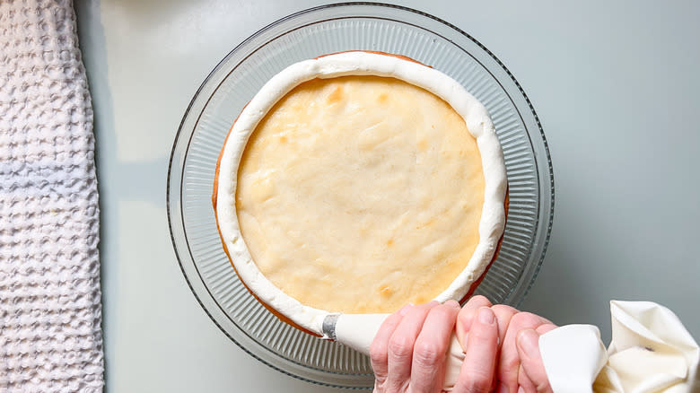 Piping buttercream around the edge of a bright and sunny lemon lavender cake layer with a pastry bag