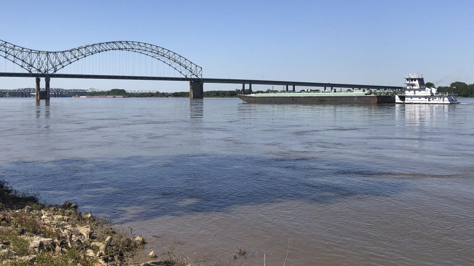 A boat hauling barges down the Mississippi River moves toward the Interstate 40 bridge linking Tennessee and Arkansas on Friday, May 14, 2021, in Memphis, Tenn. The U.S. Coast Guard reopened a section of the river near Memphis on Friday, three days after river traffic was shut down when a crack was found in the bridge. (AP Photo/Adrian Sainz)