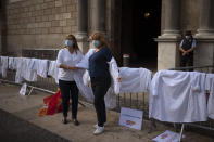 Health workers remove their doctor coats in front of the Palace of the Generalitat, the headquarter of the Government of Catalonia, as they take part in a protest against their working conditions in Barcelona, Spain, Thursday, Oct. 29, 2020. As more of Spain's regions apply border transit restrictions, the government is seeking parliamentary approval to extend the country's newly declared state of emergency to rein in the resurging coronavirus pandemic until May, a proposal that is rejected by some opposition parties. (AP Photo/Emilio Morenatti)