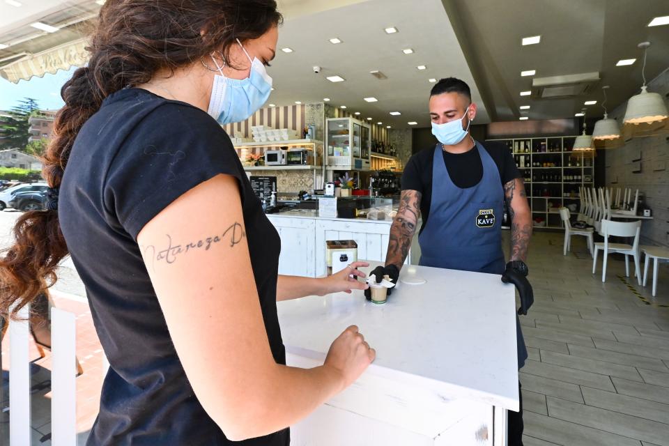 A waitress handles a takeaway coffee at a pastry shop in the Portuense district of Rome on Monday.