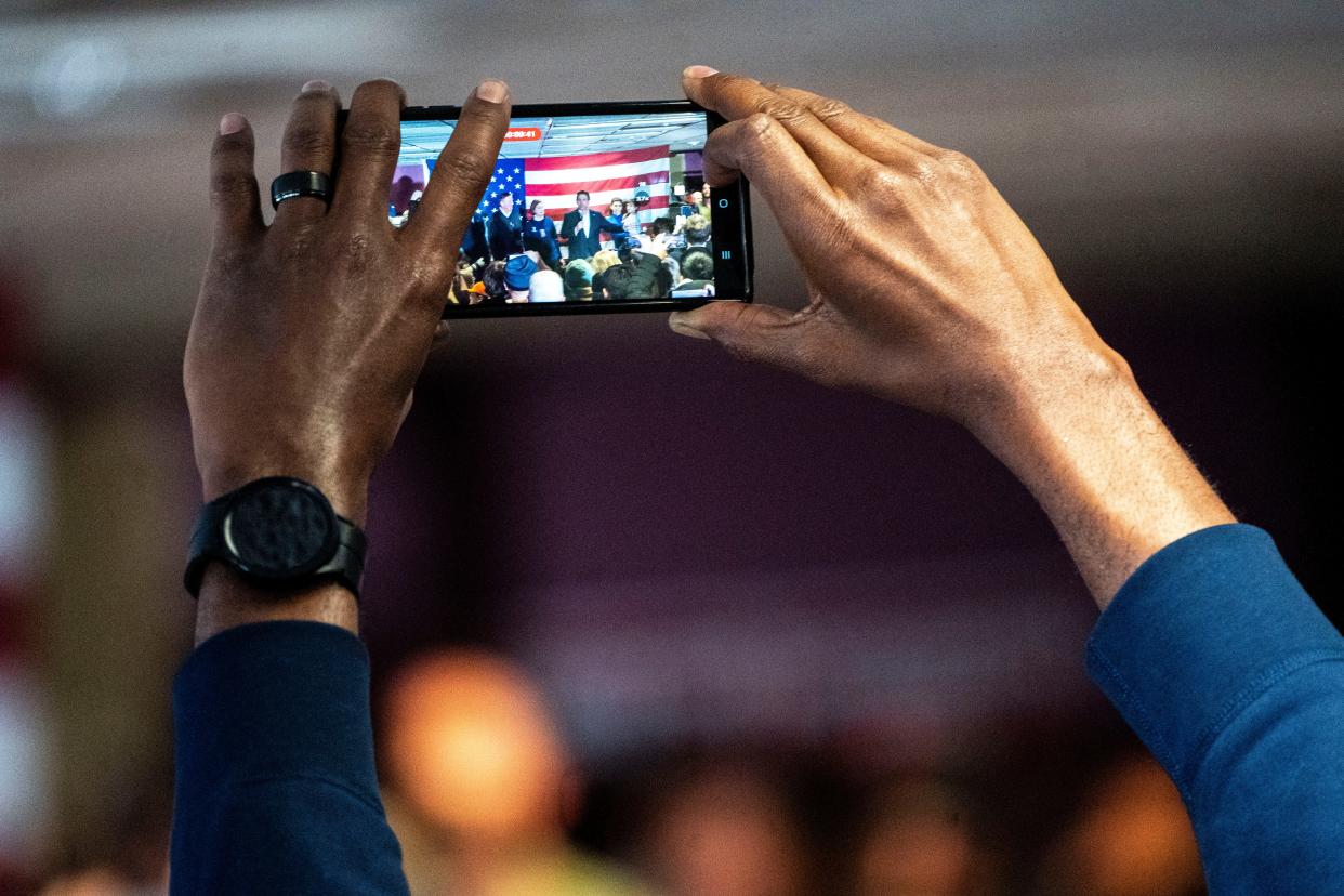 A person takes a photos as Florida Gov. Ron DeSantis speaks to a packed room Saturday, Jan. 13, 2024, at the Never Back Down Campaign Headquarters in West Des Moines.