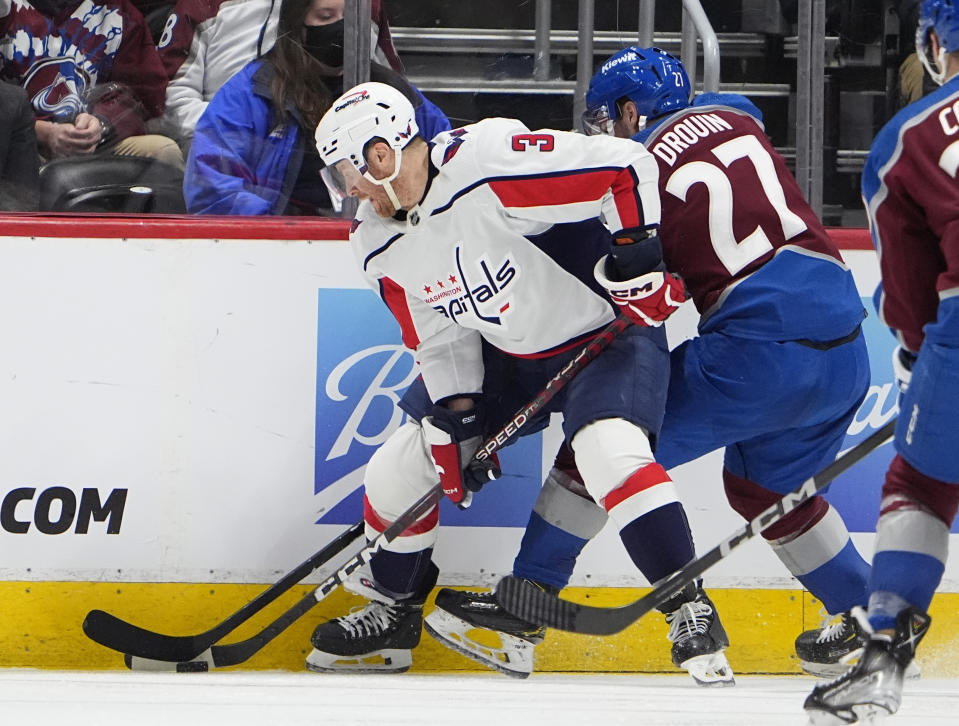 Washington Capitals defenseman Nick Jensen, left, struggles to control the puck as Colorado Avalanche left wing Jonathan Drouin defends in the second period of an NHL hockey game Wednesday, Jan. 24, 2024, in Denver. (AP Photo/David Zalubowski)