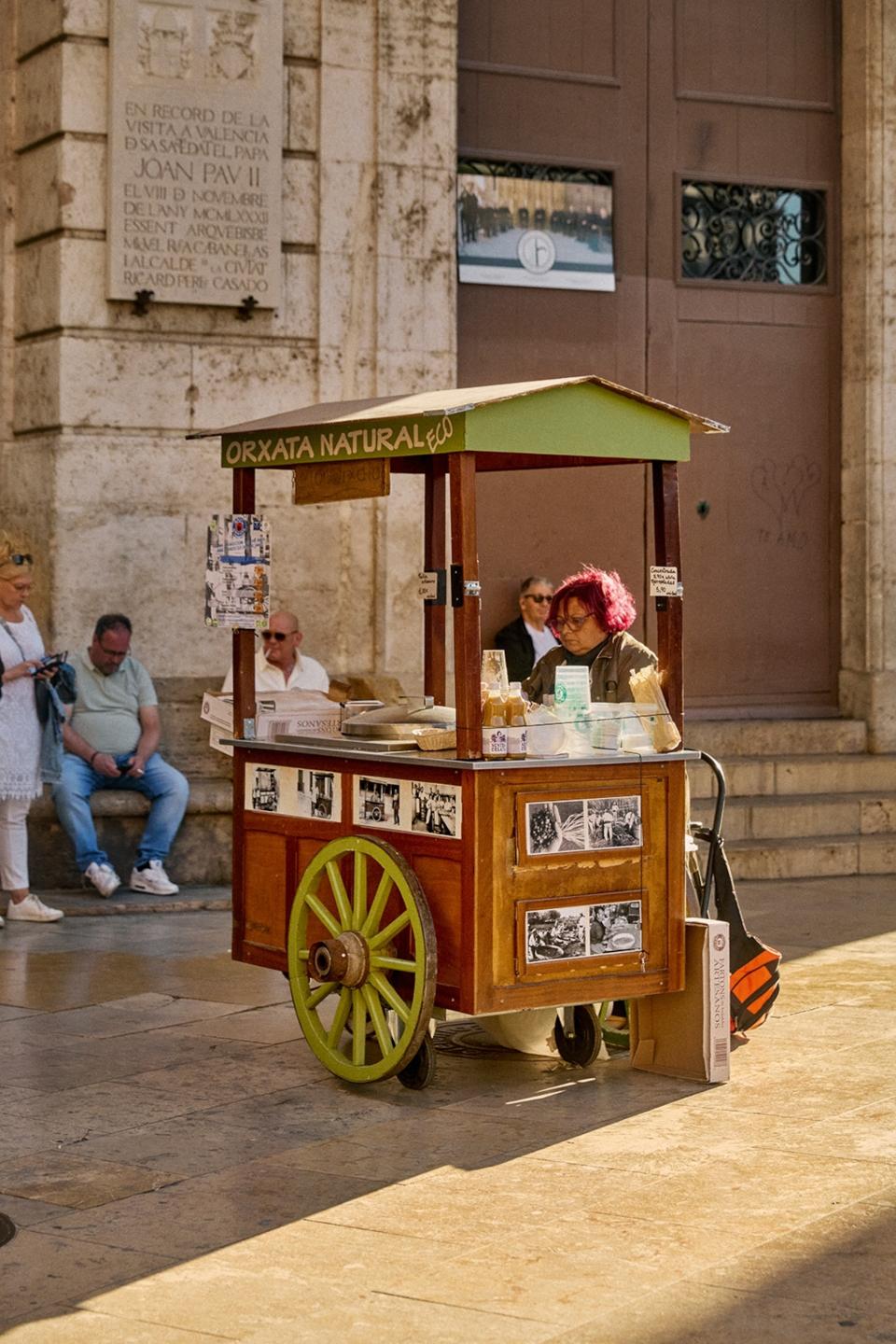 Woman selling drinks from a carriage market stall in a square