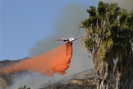 An air tanker makes waters drops as firefighters battle a fast-moving California wildfire, so-called the "Colby Fire", in the hills of Glendora January 16, 2014. REUTERS/Gene Blevins