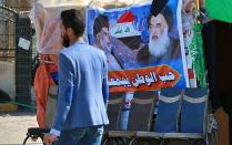 In this Sunday, Feb. 2, 2020 photo, a poster of Shiite spiritual leader Grand Ayatollah Ali al-Sistani, right, and Arabic that reads, "the love of the country bonds us together," is hung in a site of protests, in Najaf, Iraq. Grand Ayatollah Ali al-Sistani, Iraq’s top Shiite cleric, turns 90 this year, and when he recently had surgery it sent chills around the country and beyond. What happens when al-Sistani is gone? Iran is likely to try to exploit the void to gain followers among Iraq’s Shiites. Standing in its way is the Hawza, the centuries-old institution of religious learning which al-Sistani heads and which follows its own tradition-bound rules. (AP Photo/Hadi Mizban)