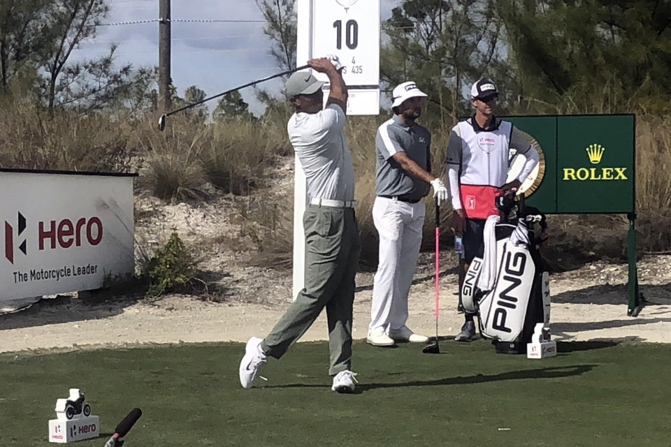 Tiger Woods tees off at the 10th hole of Albany Golf Club as Bubba Watson and his caddie look during the second round of the Hero World Challenge in Nassau, Bahamas, Thursday Dec. 5 2019. (AP Photo/Doug Ferguson)