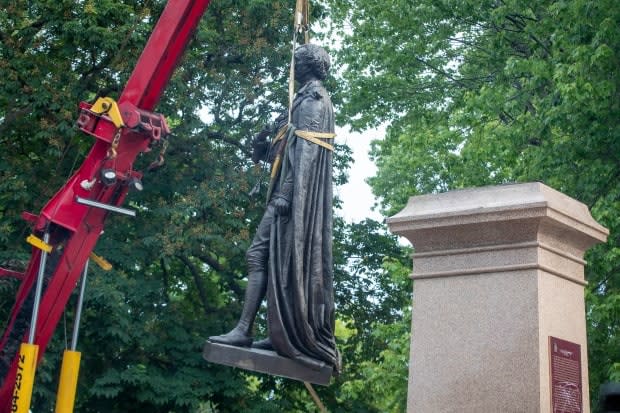 The statue of Sir John A. Macdonald is taken off its pedestal in Kingston, Ont., on Friday.  (Lars Hagberg/The Canadian Press - image credit)
