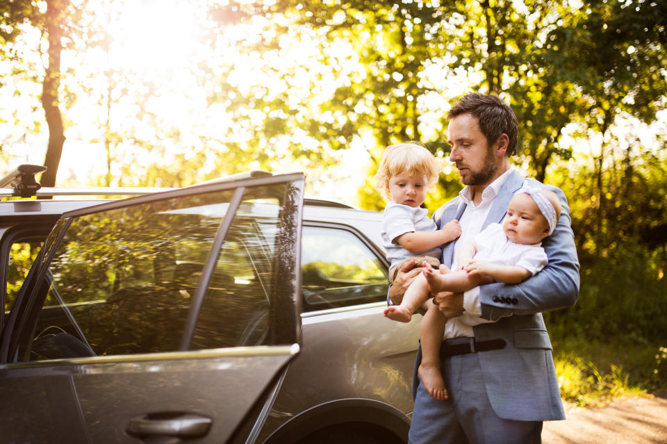 Working dad juggling toddler and baby in his arms