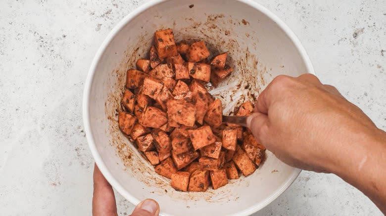 tossing sweet potatoes in oil and spices