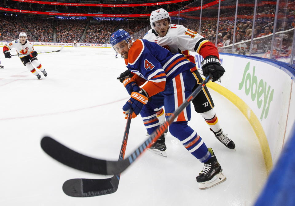 Calgary Flames' Derek Ryan (10) and Edmonton Oilers' Kris Russell (4) battle for the puck during first period NHL action in Edmonton on Sunday, Dec. 9, 2018. (Jason Franson/The Canadian Press via AP)