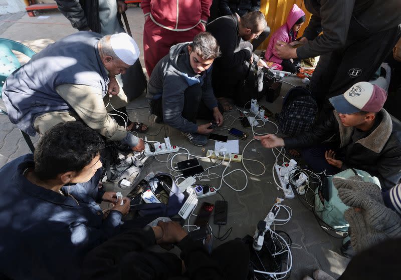 Palestinians charge their devices outside the Emirati hospital in Rafah