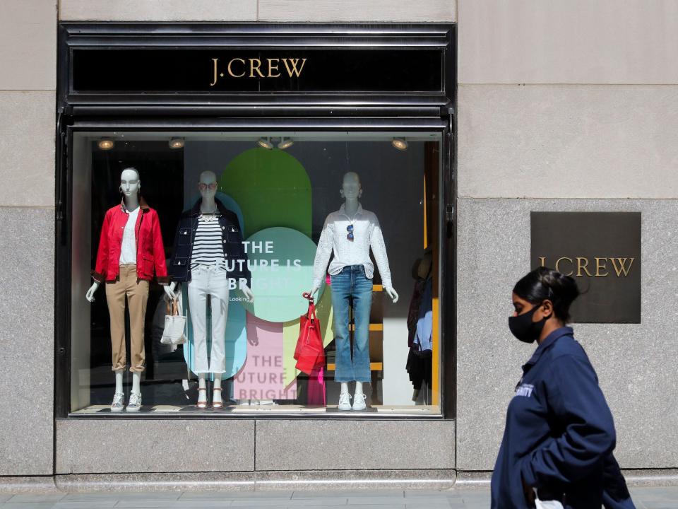 Woman wearing mask walks past J. Crew store that's window says "the future is bright"