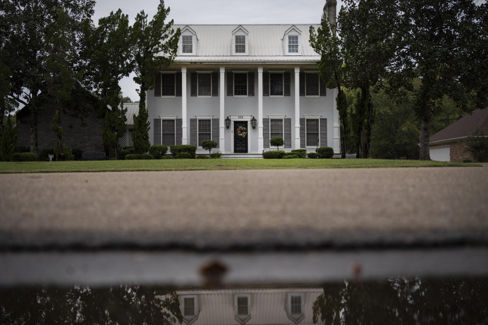 The house of Mike and Bonnie Bishop is reflected in a puddle, Friday, Oct. 9, 2020, in Byram, Miss. They met more than 25 years ago when she was organizing a basketball game to support an adopt-a-school program run by AT&T. She worked there until retiring a couple years ago. He still works there as a digital technician. (AP Photo/Wong Maye-E)