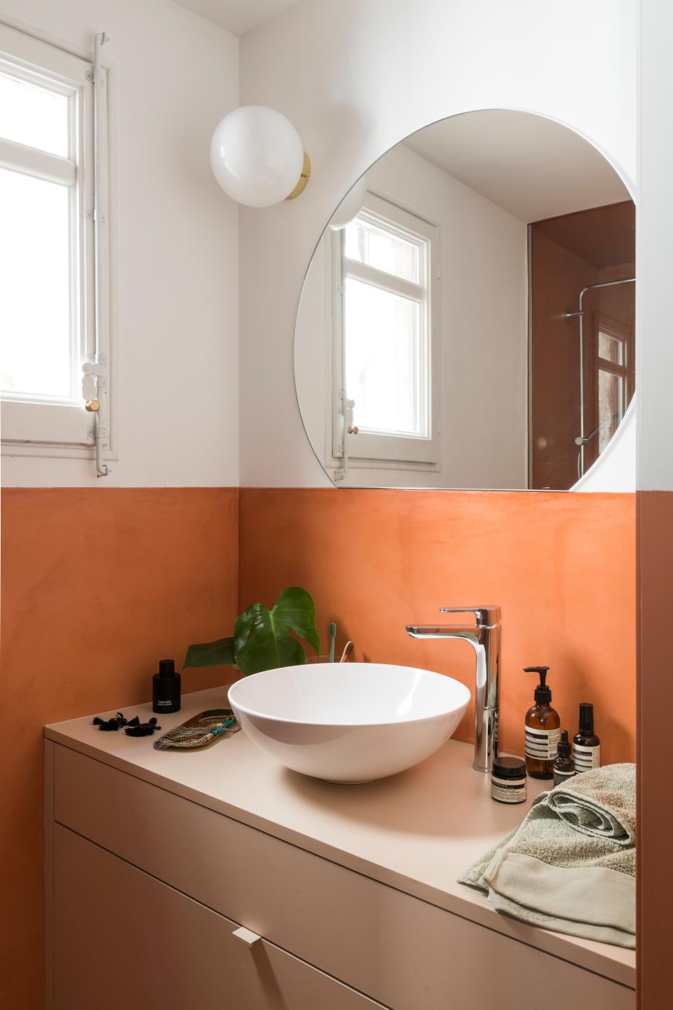 The bathroom has the same microcement feature as the kitchen backsplash, and its terra-cotta and blush shades tie in with the more public areas of the home.