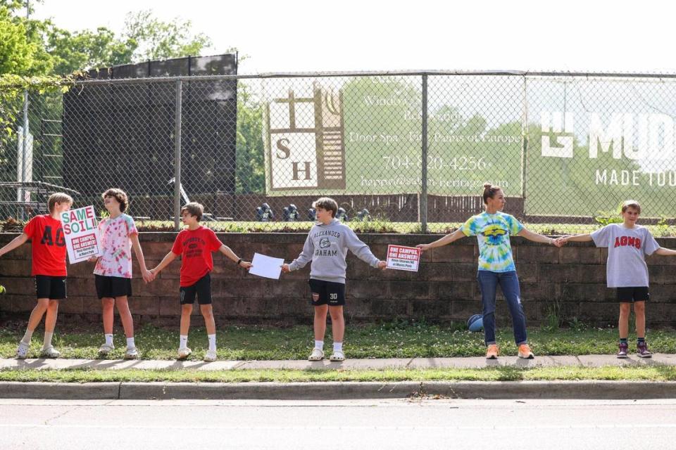 Parents and students form a human chain along Colony Road, between Alexander Graham Middle School and Myers Park High School, to demonstrate they are “one campus” on Tuesday, May 30, 2023.. Melissa Melvin-Rodriguez