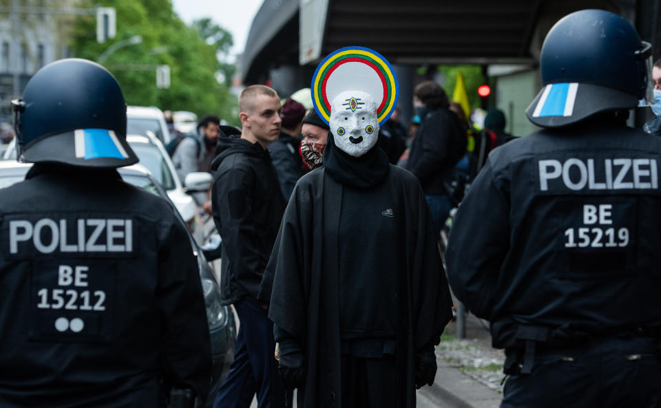 01 May 2020, Berlin: A demonstrator in disguise stands opposite police officers on the street. Due to the Corona crisis and contact restrictions, a demonstration in Oranienstraße was called via the Internet. The protest is supposed to be a substitute for the usual "Revolutionary May Day Demonstration" against capitalism. Photo: Christophe Gateau/dpa (Photo by Christophe Gateau/picture alliance via Getty Images)