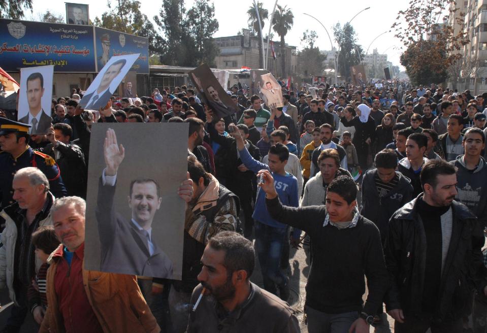 In this photo released by the Syrian official news agency SANA, pro-government Syrian protesters hold portraits of Syrian President Bashar Assad as they march during a demonstration at Kafar Souseh neighborhood in Damascus, Syria, Friday, Feb. 7, 2014. The Syrian government announced it will take part in a second round of peace talks in Geneva on Monday. The first face-to-face U.N.-hosted talks adjourned on Jan. 31. (AP Photo/SANA)