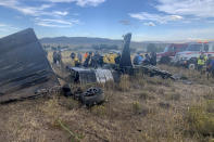 In this photo provided by the Truckee, Calif., Meadows Fire and Rescue Department, members of the Truckee Meadows Fire and Rescue Department and other officials look over aircraft wreckage, Sunday, Sept. 17, 2023, in Reno, Nev., after two California pilots were killed when their planes collided in mid-air while preparing to land after completing a race at the National Championship Air Races north of Reno. (Adam R. Mayberry/Truckee Meadows Fire and Rescue via AP)