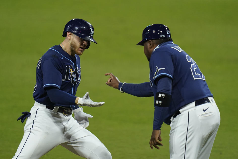 Michael Brosseau es felicitado por el coach de la antesala Rodney Linares, tras conectar un jonrón solitario por los Rays de Tampa Bay en el quinto partido de la serie divisional ante los Yanquis de Nueva York, el viernes 9 de octubre de 2020 (AP Foto/Gregory Bull)