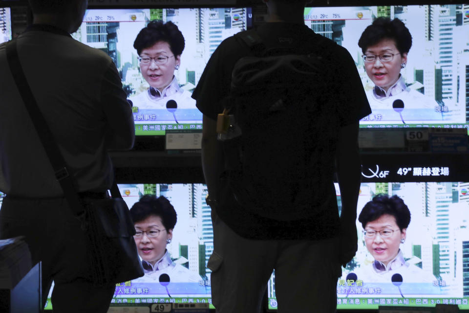 Residents watch a broadcast of Chief Executive Carrie Lam speaking at a press conference held in Hong Kong on Saturday, June 15, 2019. Lam said she will suspend a proposed extradition bill indefinitely in response to widespread public unhappiness over the measure, which would enable authorities to send some suspects to stand trial in mainland courts. (AP Photo/Vincent Yu)