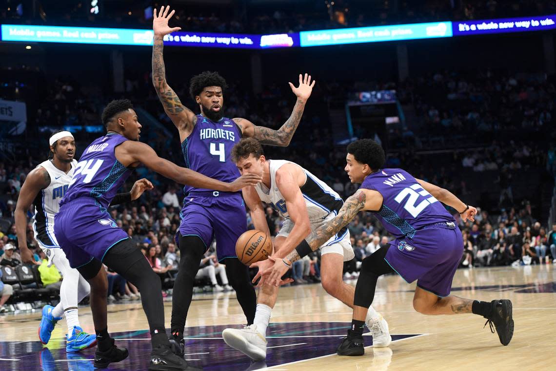 Brandon Miller (24), Nick Richards (4) and Tre Mann (23) help strip the ball from Orlando Magic forward Franz Wagner (22) during the first half on Tuesday at Spectrum Center.