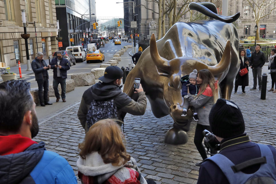 People pose for photos with the Charging Bull statue in New York's Financial District, Sunday, March 15, 2020. New York Gov. Andrew Cuomo. Cuomo said Saturday that more than 600 New Yorkers have been diagnosed with COVID-19, the disease caused by the virus. (AP Photo/Richard Drew)