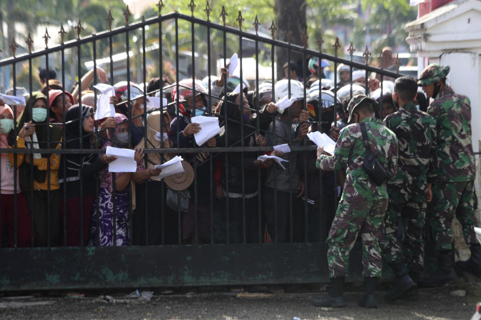 People affected by earthquake queue up for relief goods in Mamuju, West Sulawesi, Indonesia, Monday, Jan. 18, 2021. Aid was reaching the thousands of people left homeless and struggling after an earthquake that killed a number of people in the province where rescuers intensified their work Monday to find those buried in the rubble. (AP Photo/Joshua Marunduh)